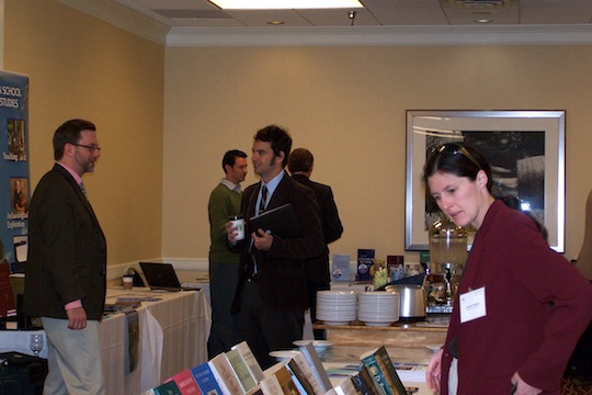Adults browse and converse beside tables displaying books.