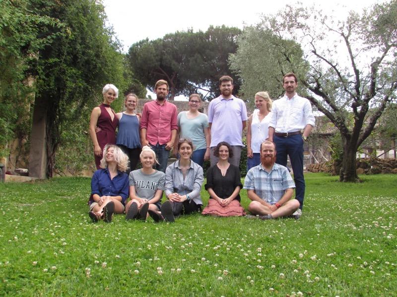 A group of adults poses on a lawn in a garden.