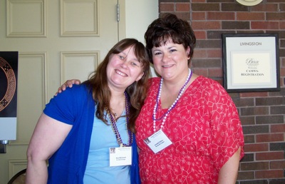 Two adults wearing conference badges pose together indoors.